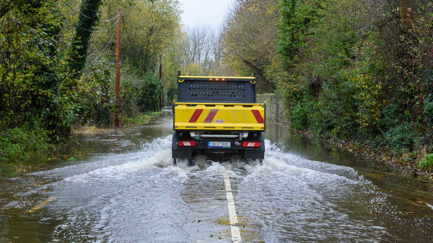 A truck drives on a flooded road
